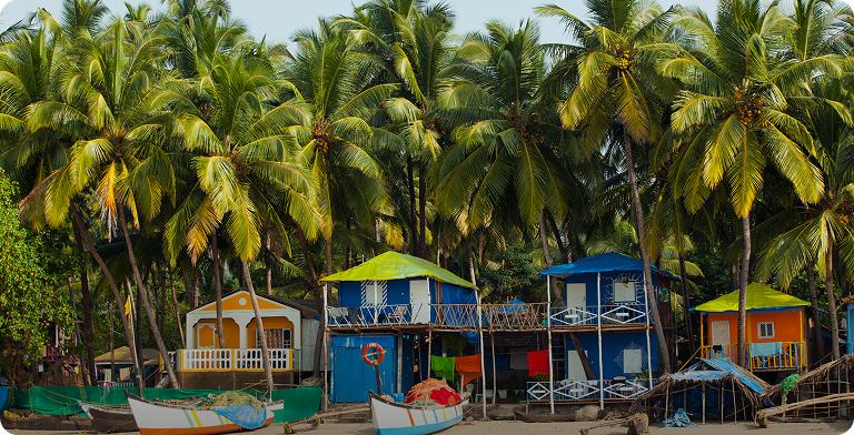 Kolorowe domki wśród palm na plaży w Goa w Indiach