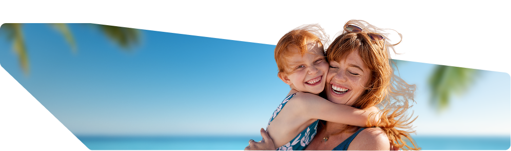 Uśmiechnięta kobieta przytulająca córkę na tle plaży i błękitnego morza w słoneczny dzień, zapowiedź wakacji Lato 2026