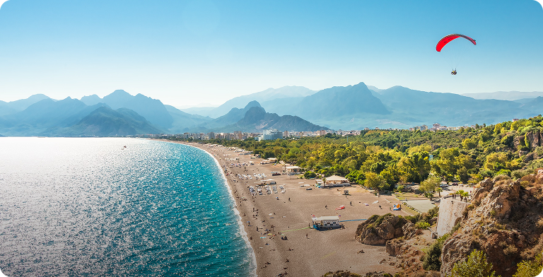 Panorama tureckiego wybrzeża z plażą w kształcie półksiężyca otoczoną zielonymi wzgórzami